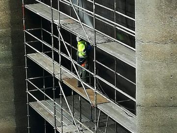Andamios con trabajador en edificio 