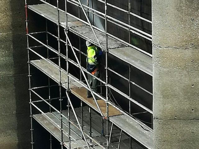 Andamios con trabajador en edificio 